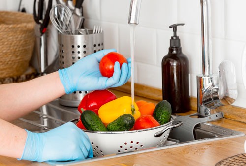 washing-vegetables-in-sink-wearing-rubber-gloves